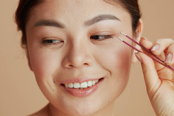 Woman applying makeup with tweezers