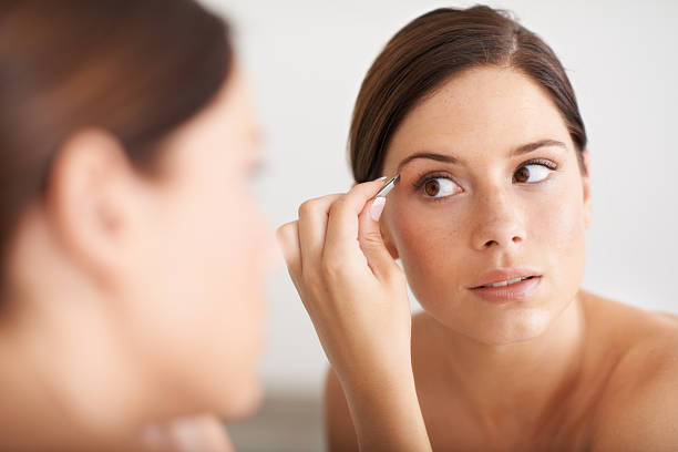 Woman applying eyebrow makeup in front of a mirror